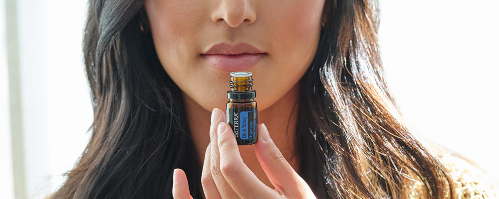Woman smelling a bottle of Blue Tansy oil.