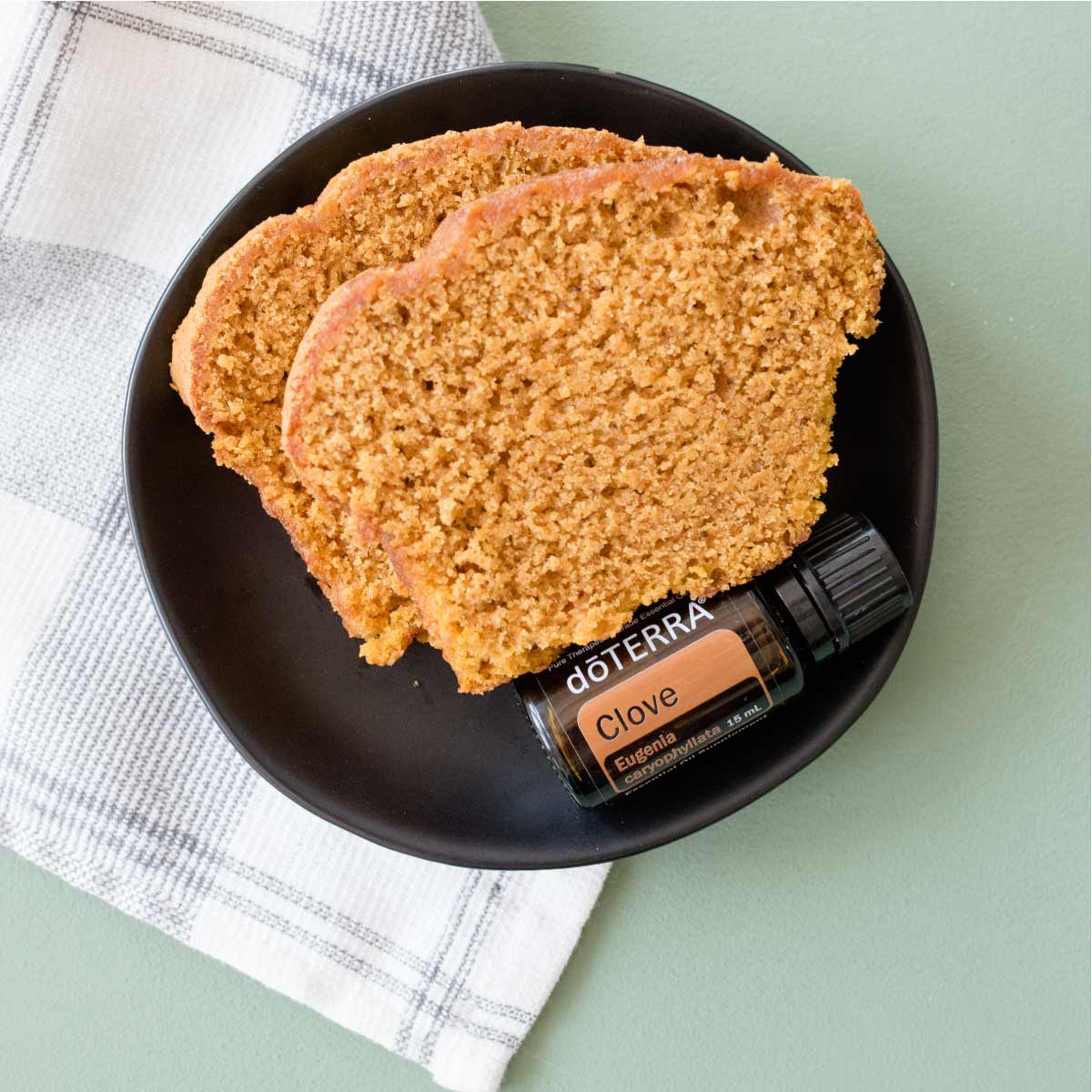 Bottle of Clove essential oil with homemade bread. Wondering how to use Clove essential oil? Clove oil can be used in oral care, adding flavor when cooking, or to create a warming massage.
