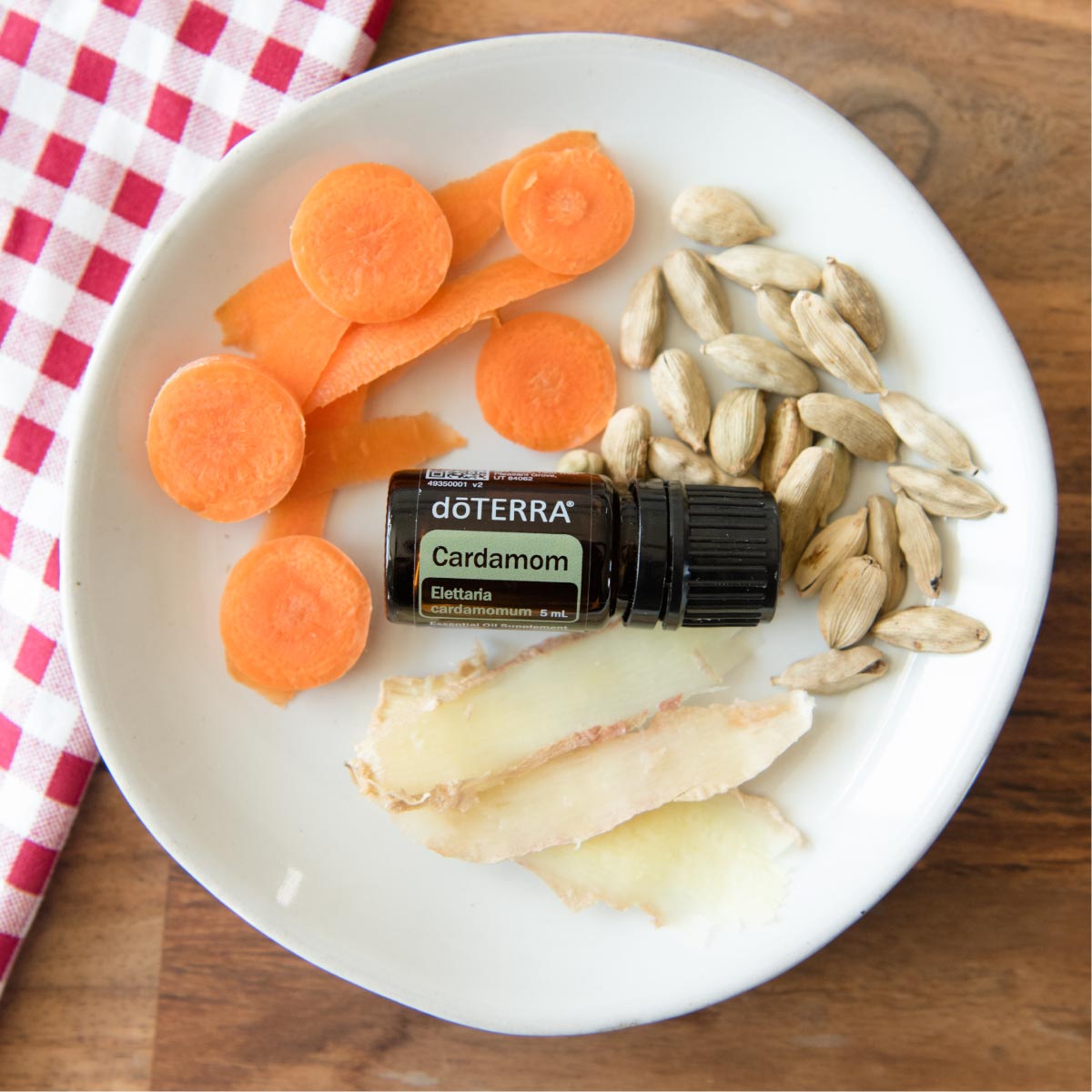 doTERRA Cardamom oil bottle on a plate with carrots, seeds, and potatoes. Wondering how to use Cardamom oil? People love to use Cardamom essential oil for cooking, to cool the skin, to aid in digestion, and more.
