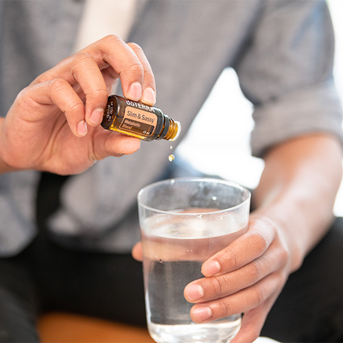 man adding one drop of essential oil to a glass of water