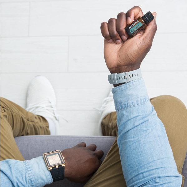 Man holding bottle of doTERRA Cypress oil. There are many benefits of cypress oil. This essential oil is known to be balancing, comforting, invigorating, and good for the skin.