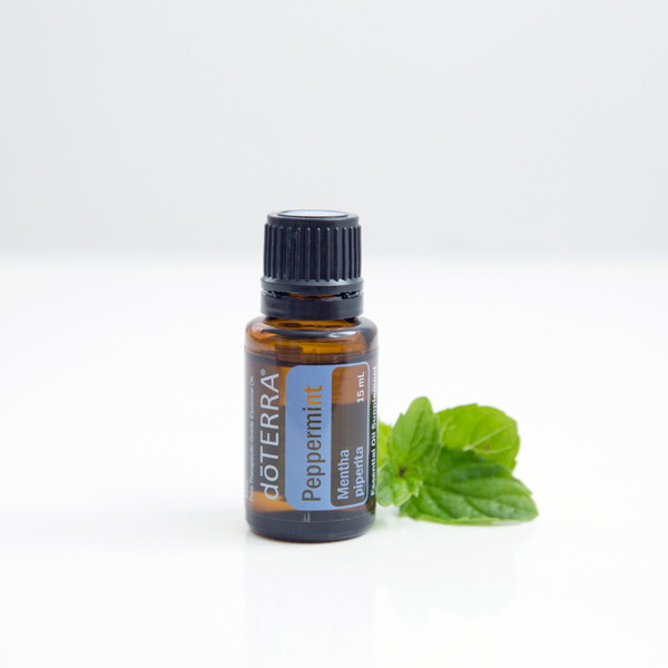 doTERRA Peppermint essential oil bottle next to green peppermint leaves. What are the uses and benefits of peppermint oil? Mint oil has dozens of uses and has been in use for many years due to its benefits for digestion, energy, oral health, reducing tension, and more.