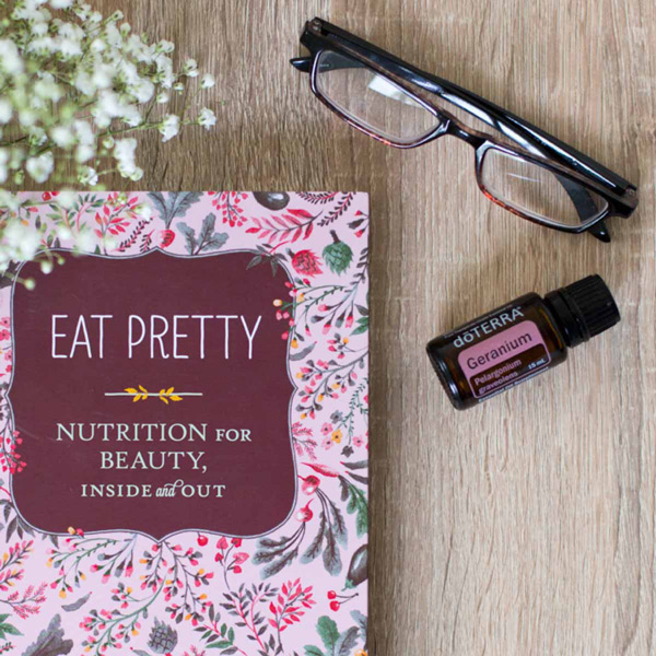 Geranium essential oil bottle, small white flowers, a pair of reading glasses, a book titled, Eat Pretty: Nutrition for Beauty, Inside and Out. What does Geranium oil smell like? Geranium essential oil has a sweet, floral aroma that is both herbaceous and rose-like.