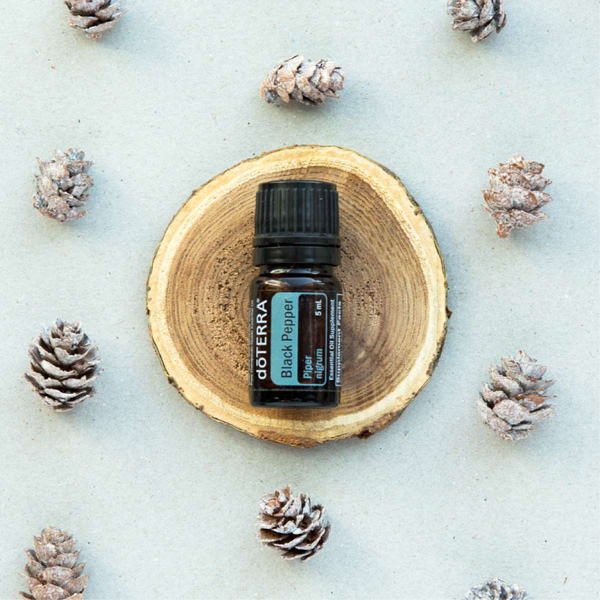 Bottle of doTERRA Black Pepper oil balanced on a piece of wood, surrounded by small pinecones. What is Black Pepper essential oil used for? Black Pepper oil can be used to add flavor to food when cooking, to ward off seasonal threats, or provide the body with antioxidants.
