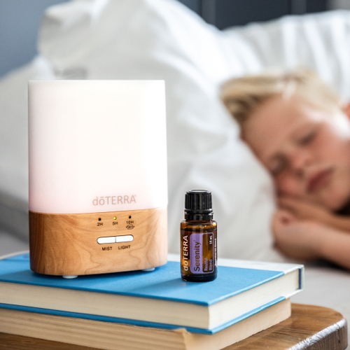 doTERRA Lumo diffuser next to a sleeping child and doTERRA Serenity oil bottle. Using an essential oil diffuser can help you to create an ideal atmosphere in your home with the inviting aroma of essential oils.