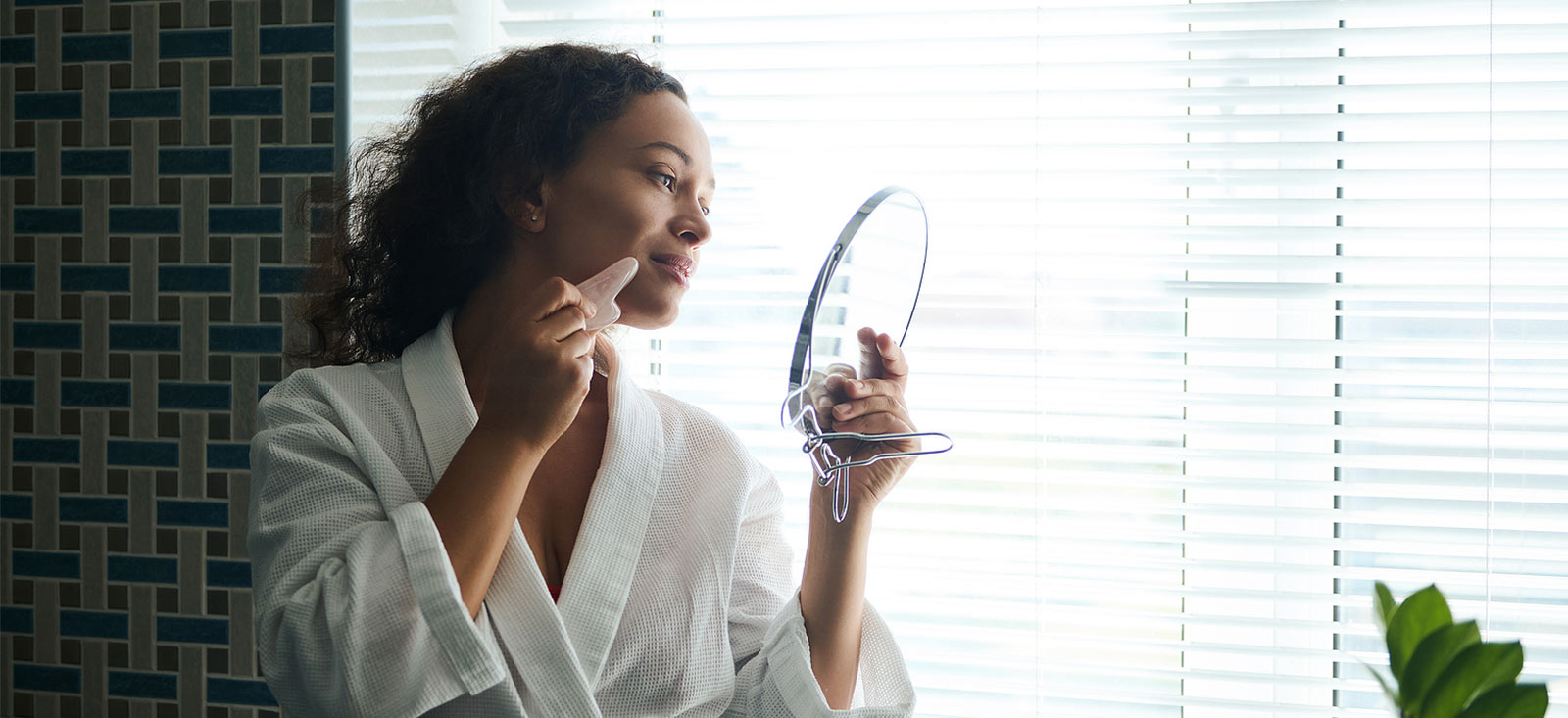 Woman looking at the mirror using gua sha