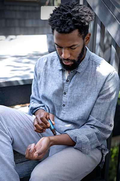 Man seated on outside steps gently rubbing Adaptiv Touch on the inside of his wrist.