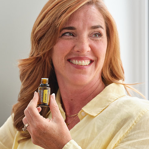 A woman smiling and smelling lemon essential oil