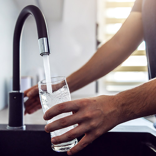 A person filling up a glass with water