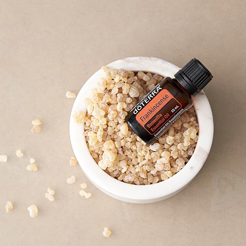doTERRA Frankincense essential oil bottle laying in a bowl of frankincense resin.