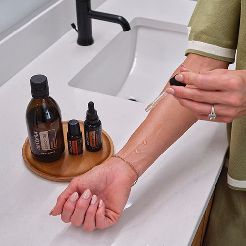 A woman putting castor oil on her arm