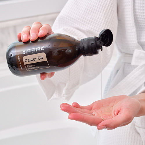 A person pouring castor oil into their hand