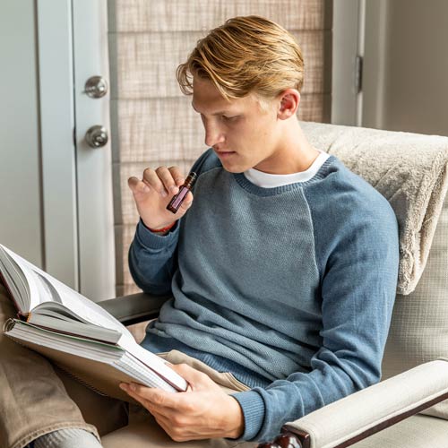 A teenager sitting and smelling essential oil while reading