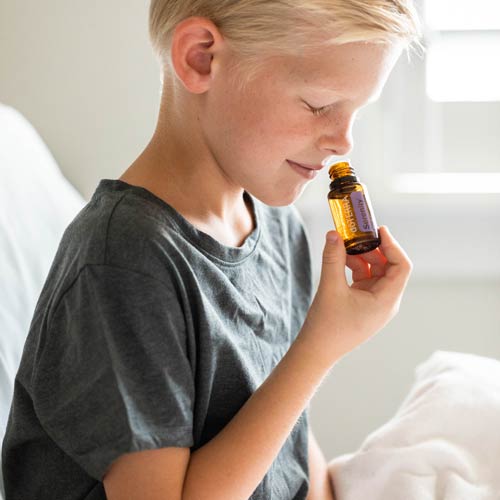 A young boy smelling Serenity essential oil