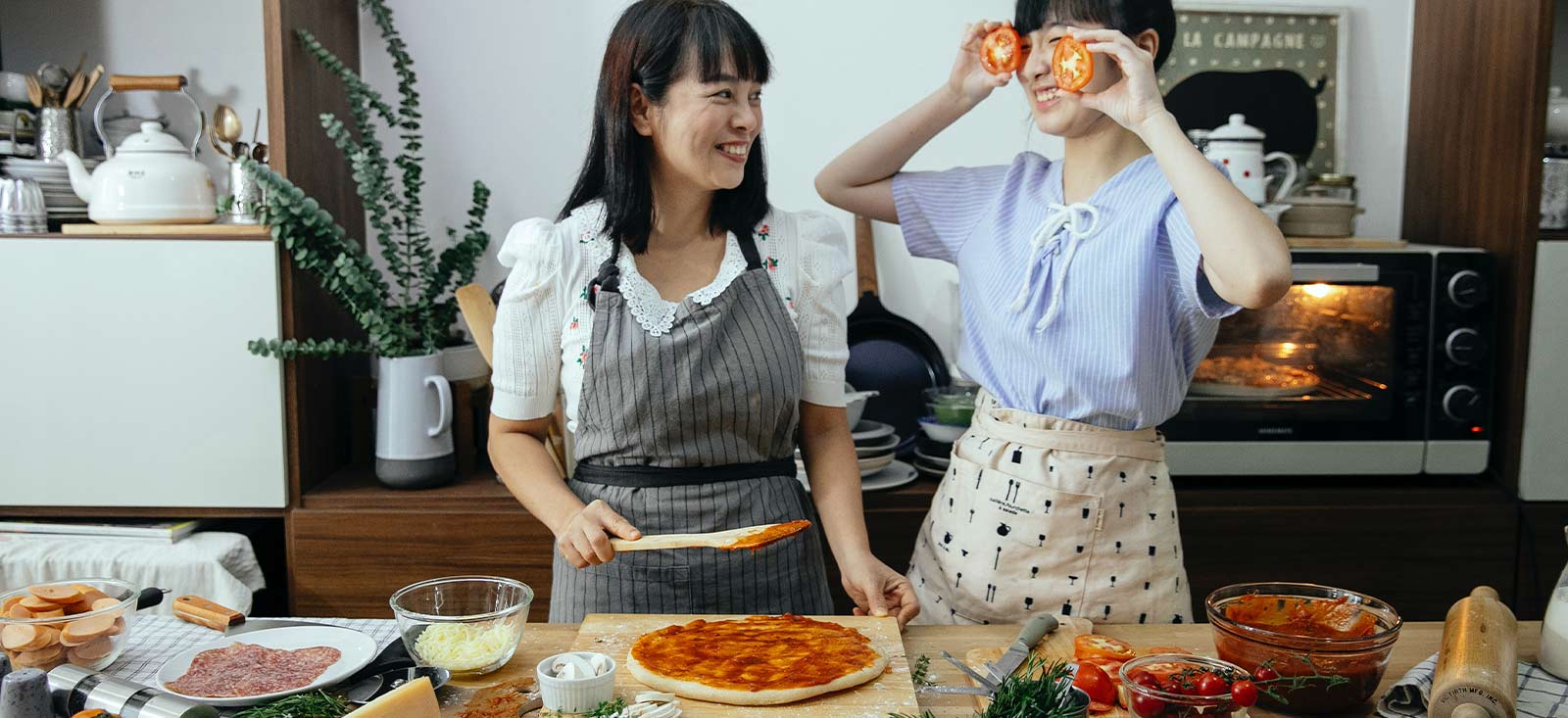 Mom and daughter having fun cooking a pizza