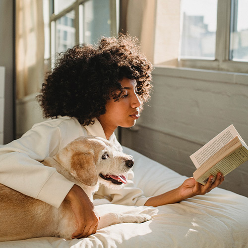 Woman reading a book beside her dog