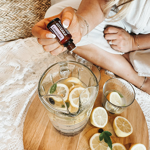Woman adding Lavender Essential Oil in a Jar of water with lemon