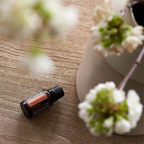 A bottle of doTERRA Frankincense essential oil on a wooden table.