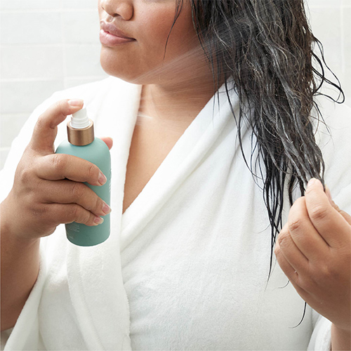 Woman using doTERRA hair leave-in conditioner
