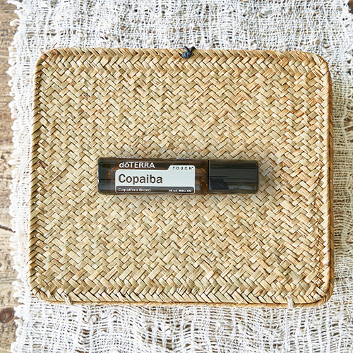 Bottle of doTERRA Copaiba Touch essential oil on a woven straw mat.