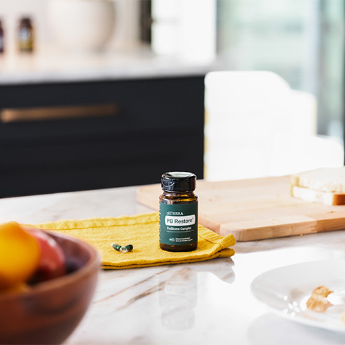A bottle of doTERRA PB Restore dietary supplement on a kitchen counter.