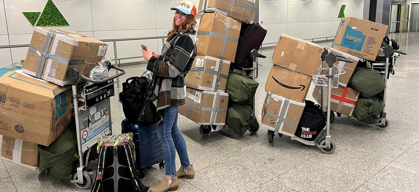 A woman with luggage and lot of boxes in an airport.