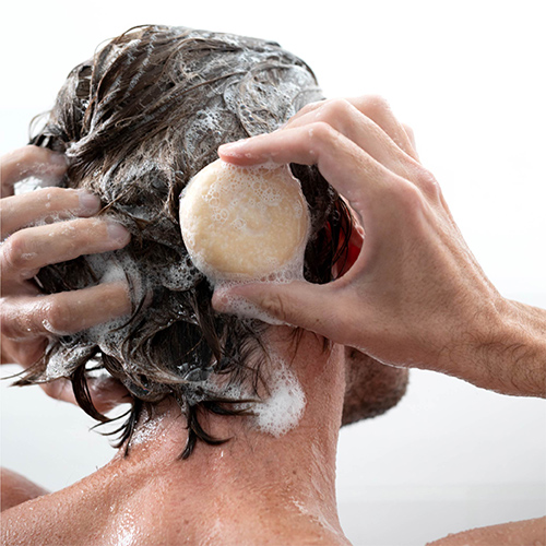 Man washing his hair with doTERRA hair shampoo bar