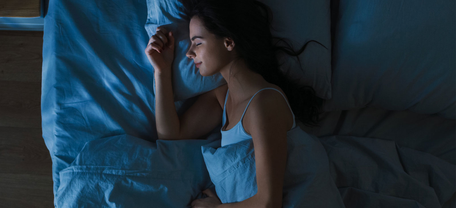 Woman sleeping peacefully in a dark room.