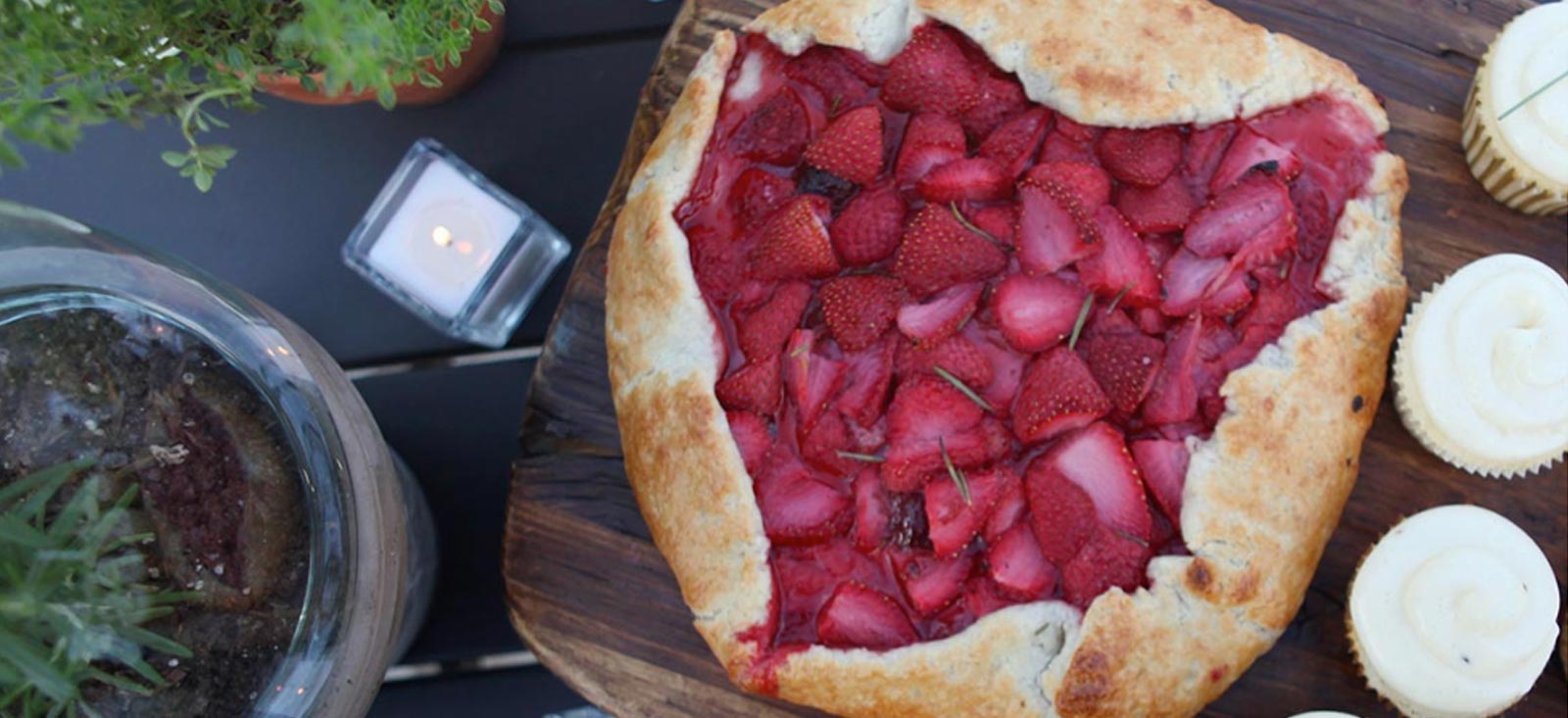 A strawberry tart on a wooden cutting board.