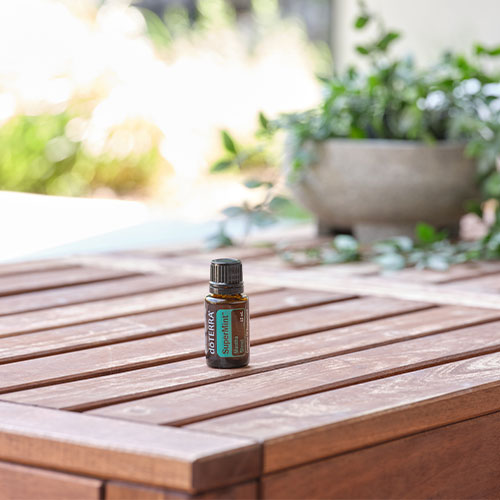 A bottle of doTERRA SuperMint essential oil sits on a wooden table.