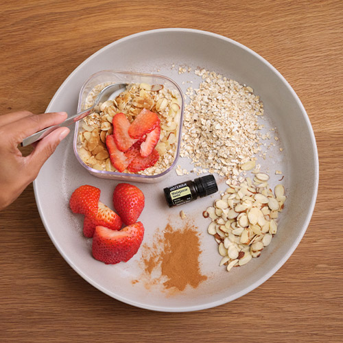 Strawberries, oats, sliced almonds, and Vanilla Essential Oil on a plate