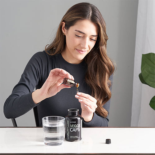 A woman pouring Ginger Essential oil into a doTERRA Veggie cap.