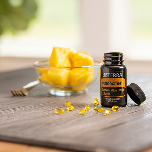 A bottle of doTERRA Zendocrine Softgels with pineapple chunks in the background.