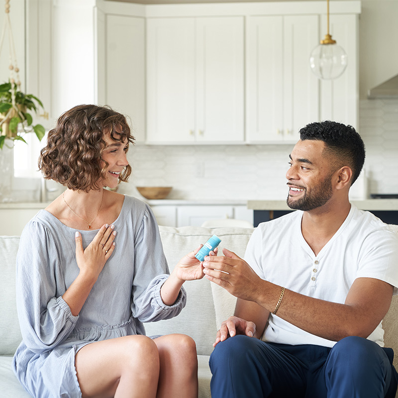 A man and a woman sitting next to each other exchanging doTERRA products.