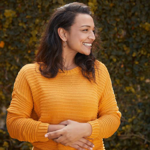 A woman in an orange sweater smiling