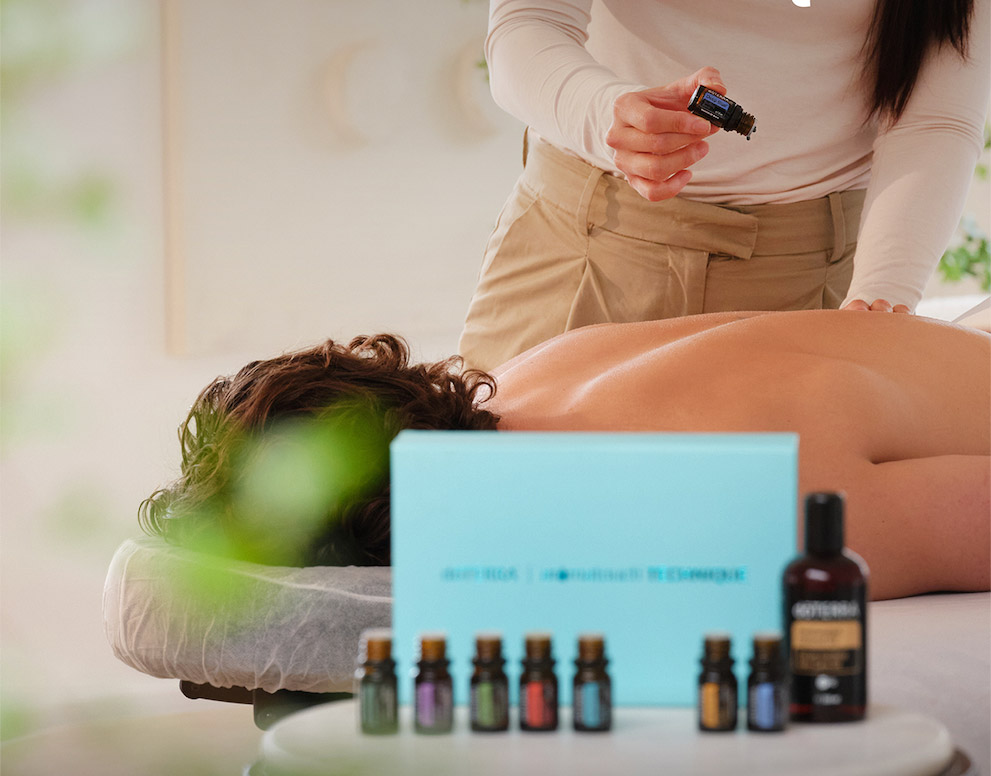 A person lying on a massage table while someone performs the AromaTouch Technique