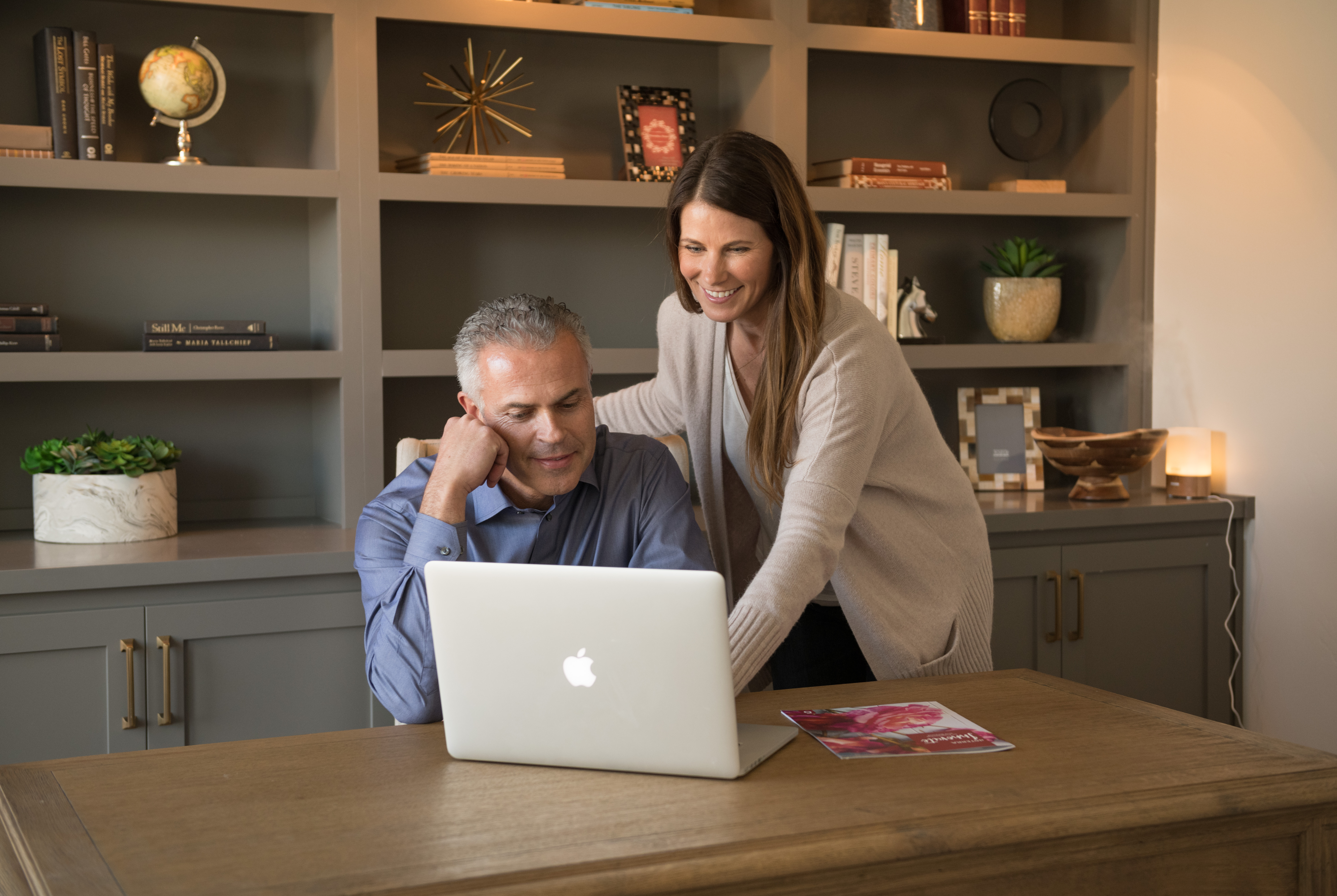 A man and woman looking at a laptop in a home office