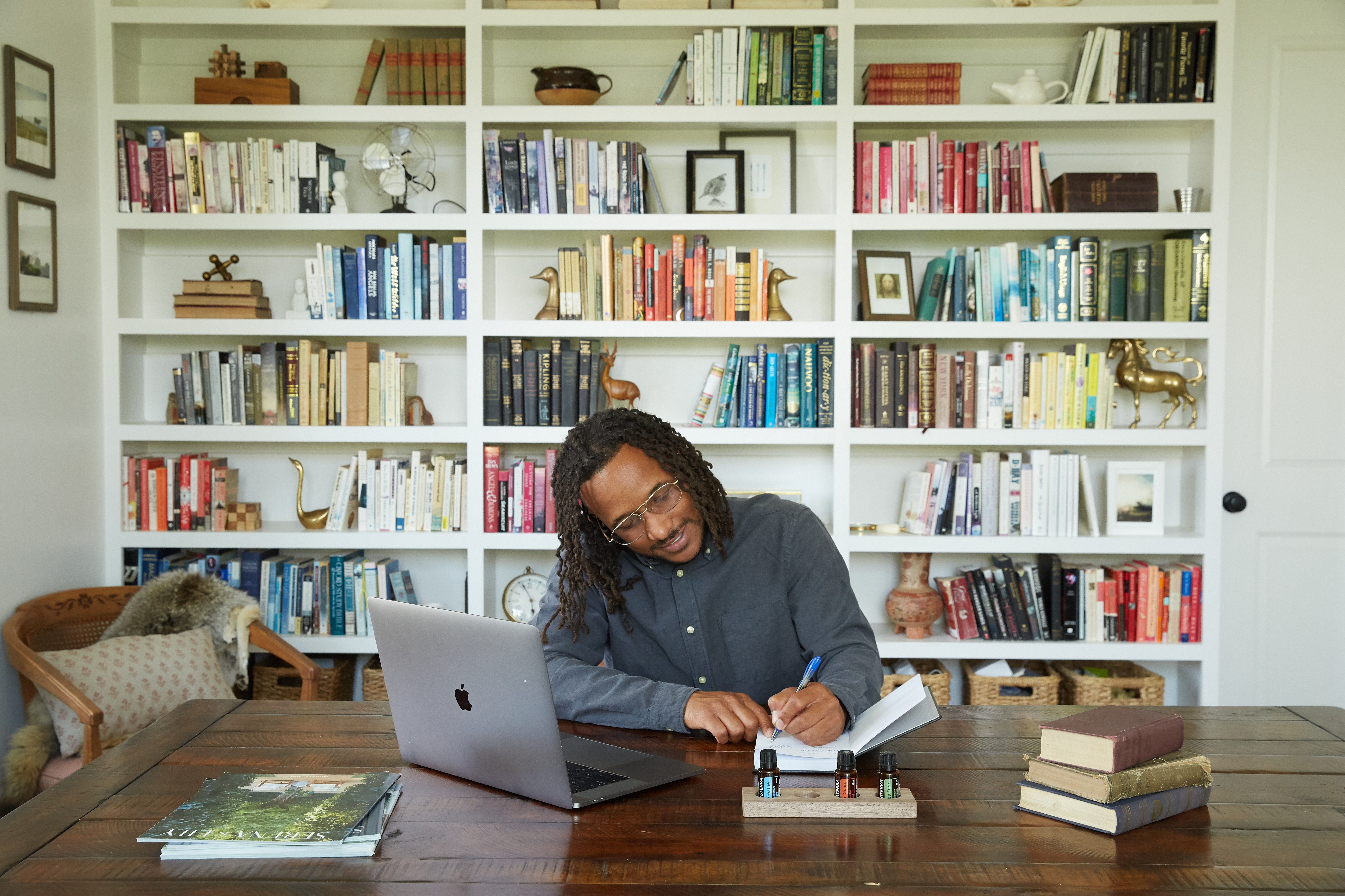 A man sitting at a desk with a laptop in front of a bookshelf