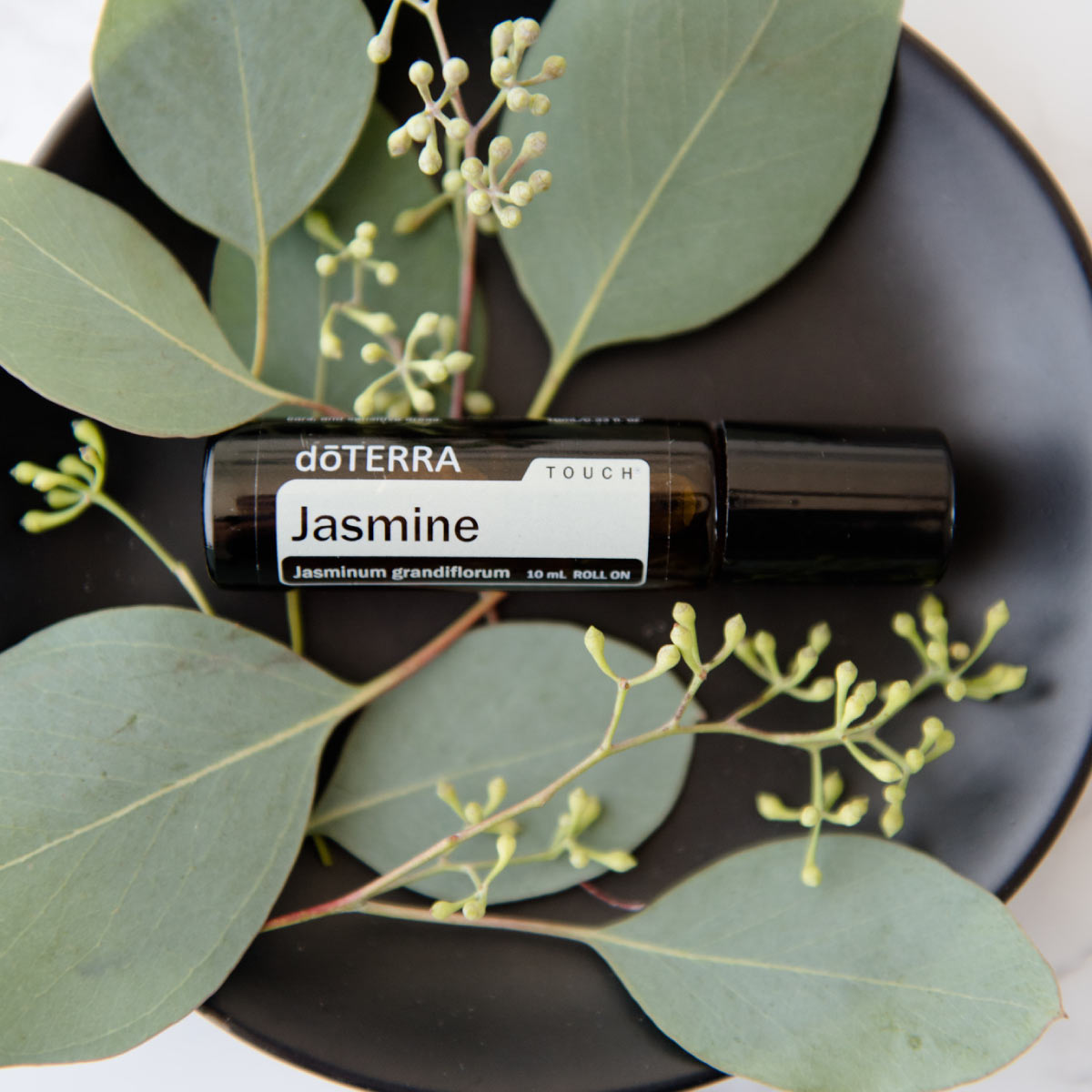 Jasmine essential oil bottle surrounded by green leaves. How do I use Jasmine essential oil? Jasmine oil can be used to reduce the appearance of skin imperfections and promote relaxation.