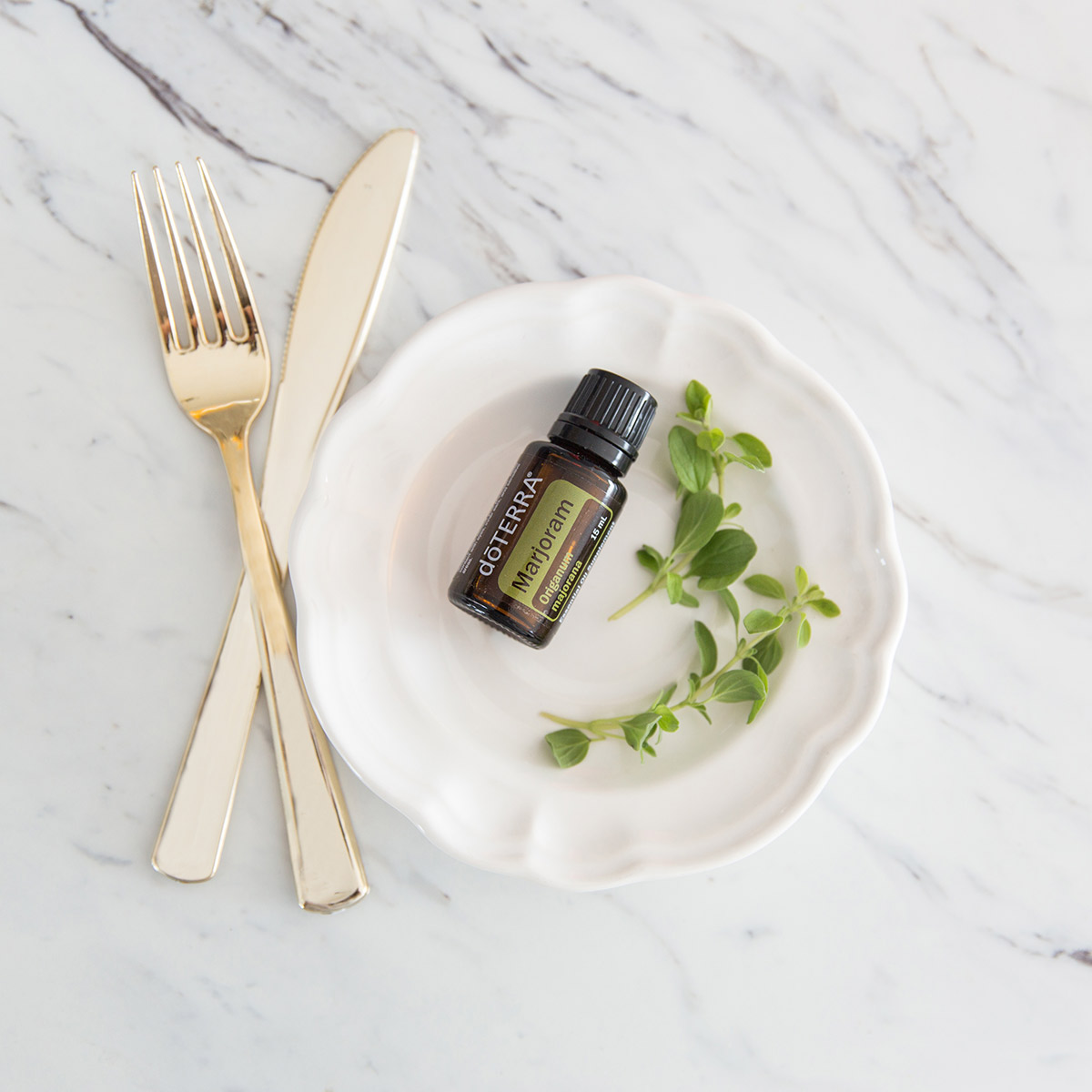 Bottle of Marjoram essential oil on a plate with fresh marjoram leaves, next to a fork and knife. How do I use marjoram essential oil? You can use Marjoram oil for cooking in place of dry marjoram.