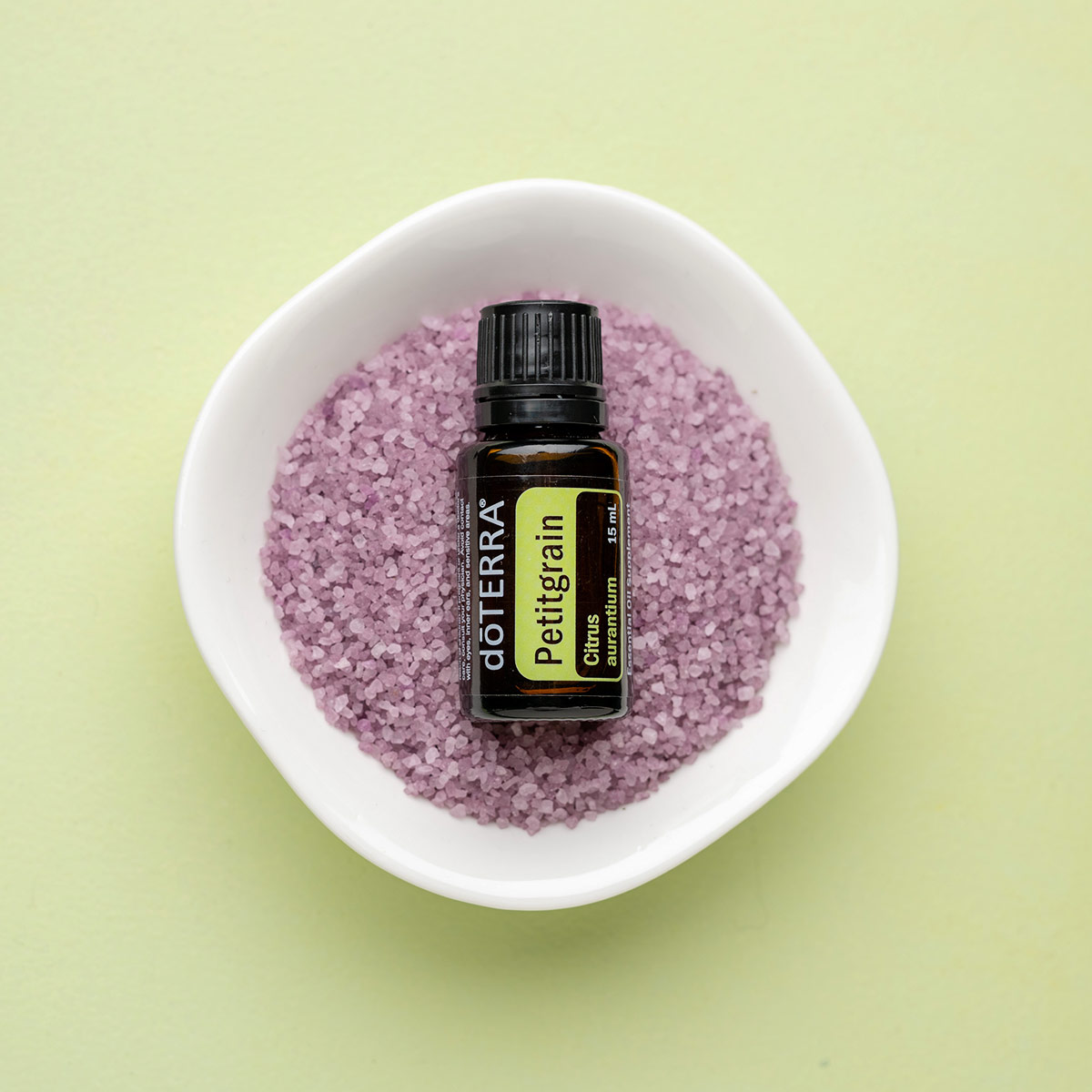 doTERRA Petitgrain essential oil bottle in a small white dish with purple bath salts. What does Petitgrain oil smell like? Petitgrain essential oil has a clean, fresh, floral aroma.
