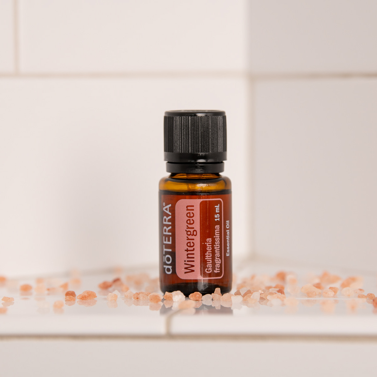 Wintergreen essential oil bottle surrounded by pink bath salts. What is Wintergreen oil? Wintergreen essential oil is derived from the leaves of a wintergreen shrub and has a sweet, minty, refreshing aroma.